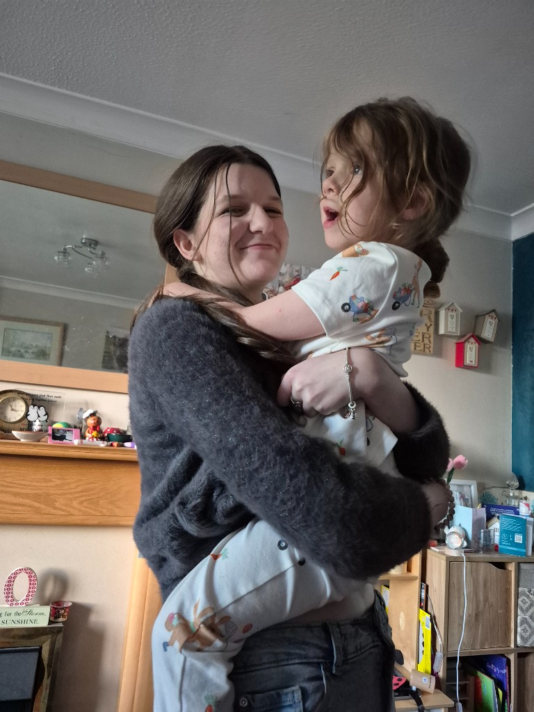 Evie smiling while holding a happy young child